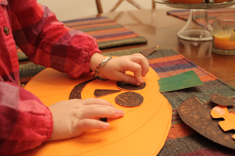 Preschool pumpkin emotion activity, child places paper pieces on a pumpkin to make a smile