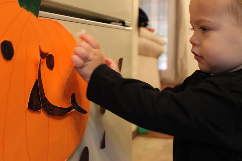 Toddler moving pumpkin face pieces to make a smile