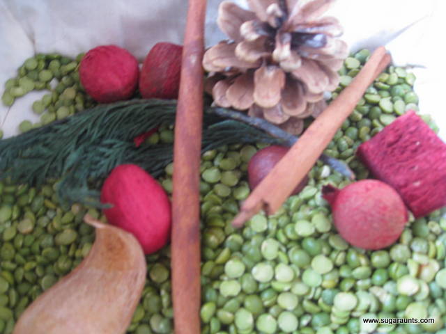 Christmas sensory bin made with green split peas, potpourri, cinnamon sticks, and pine cones