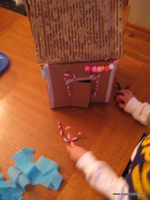 Decorate a cardboard gingerbread house with craft materials.