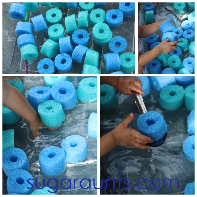 Blue and green pool noodle slices that have been cut and added to a water sensory bin. Children's hands are using ladles and large spoons to scoop the pool noodle pieces from the sensory bin.