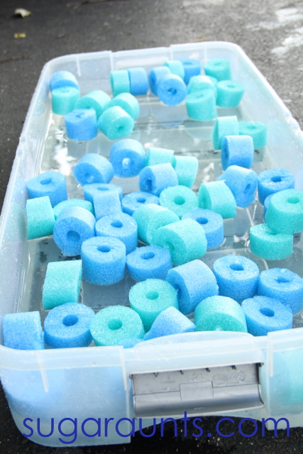 Large storage bin filled with pool noodle cut into pieces and water to create a pool noodle sensory bin