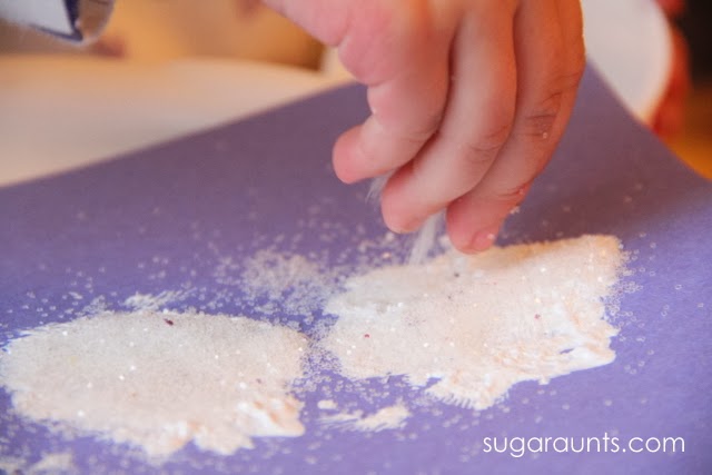 Espolvorea purpurina en la pintura para obtener una pintura casera con purpurina, ideal para una manualidad de muñeco de nieve.
