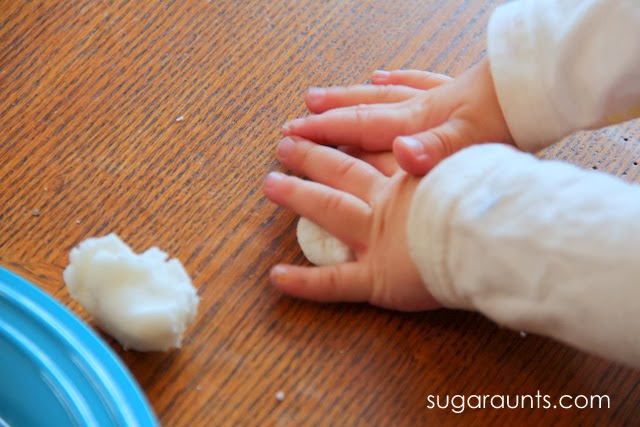 child's hands pressing lump of baking soda dough on a table