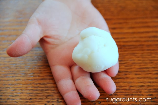 child's hand holding a ball of baking soda dough in the palm of their hand