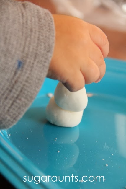 child's hand rolling baking soda dough into a snowman