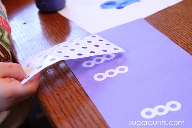 Kids can use hole reinforcement stickers to make a snowman craft and strengthen fine motor skills.