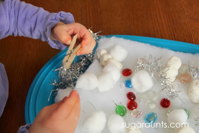 Niño manipulando piezas sueltas en un contenedor sensorial con muñecos de nieve de plastilina