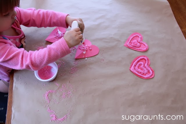Toddler squeezing glue onto construction paper hearts