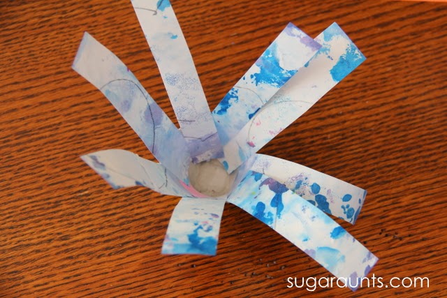 Pega tiras de proyectos artísticos reciclados en un cartón de huevos para crear una manualidad de flores de primavera.