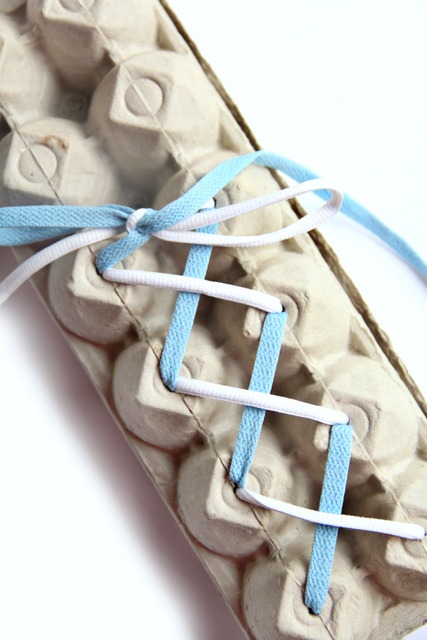 Shoe tying activity using an egg carton and two different colored laces.